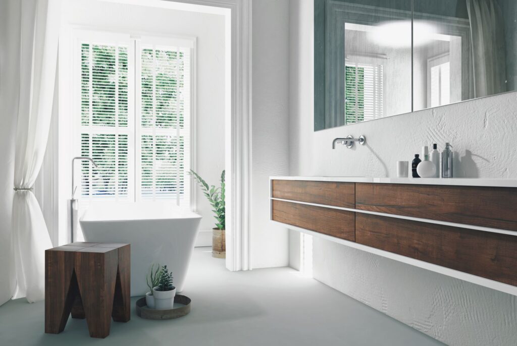 Helles und elegantes Badezimmer mit freistehender Badewanne vor einem großen Fenster, Holzdetails und modernen, in die Wand integrierten Waschtischarmaturen, die eine stilvolle und funktionale Umgebung schaffen.