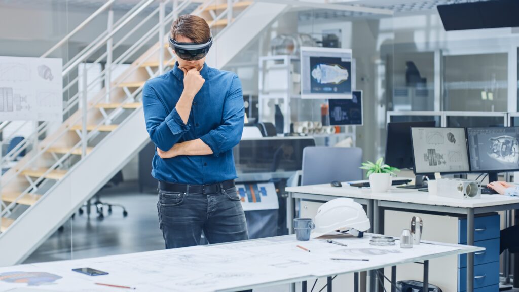 Ein Ingenieur trägt ein VR-Headset und arbeitet in einem modernen Büro an einem Projekt, unterstützt durch VR-Dienstleistungen einer VR Agentur