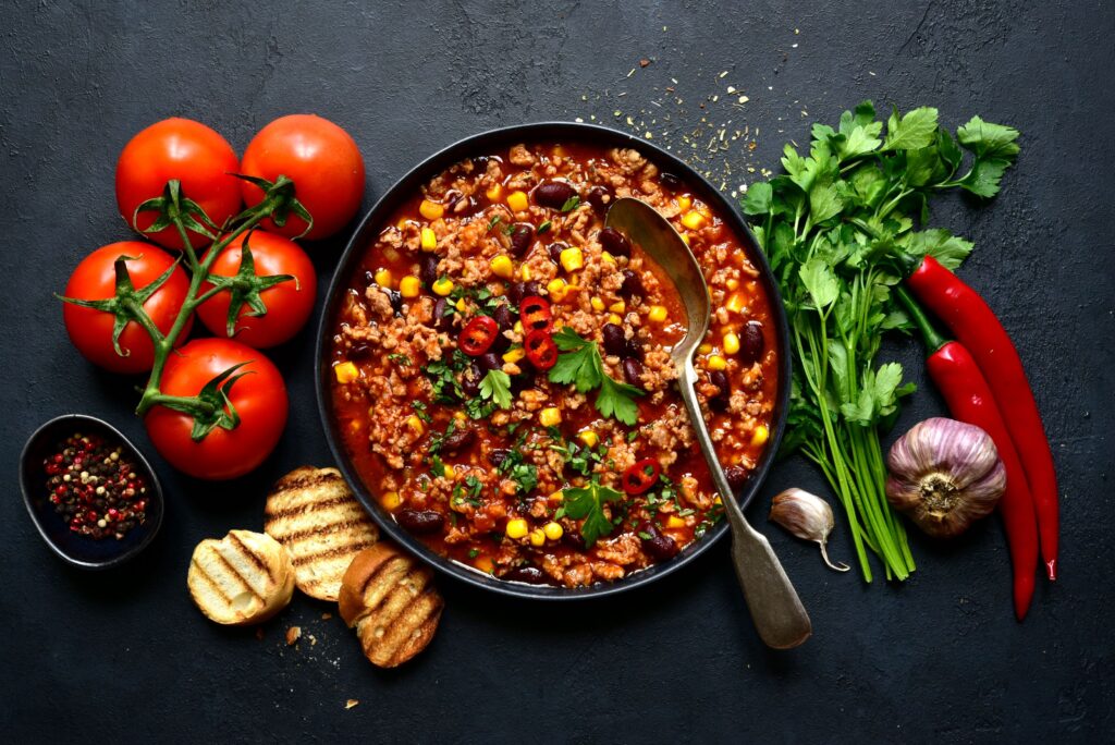 Zutaten wie Tomaten, Knoblauch, roten Chilis und Koriander mit einem mexikanischen Gericht