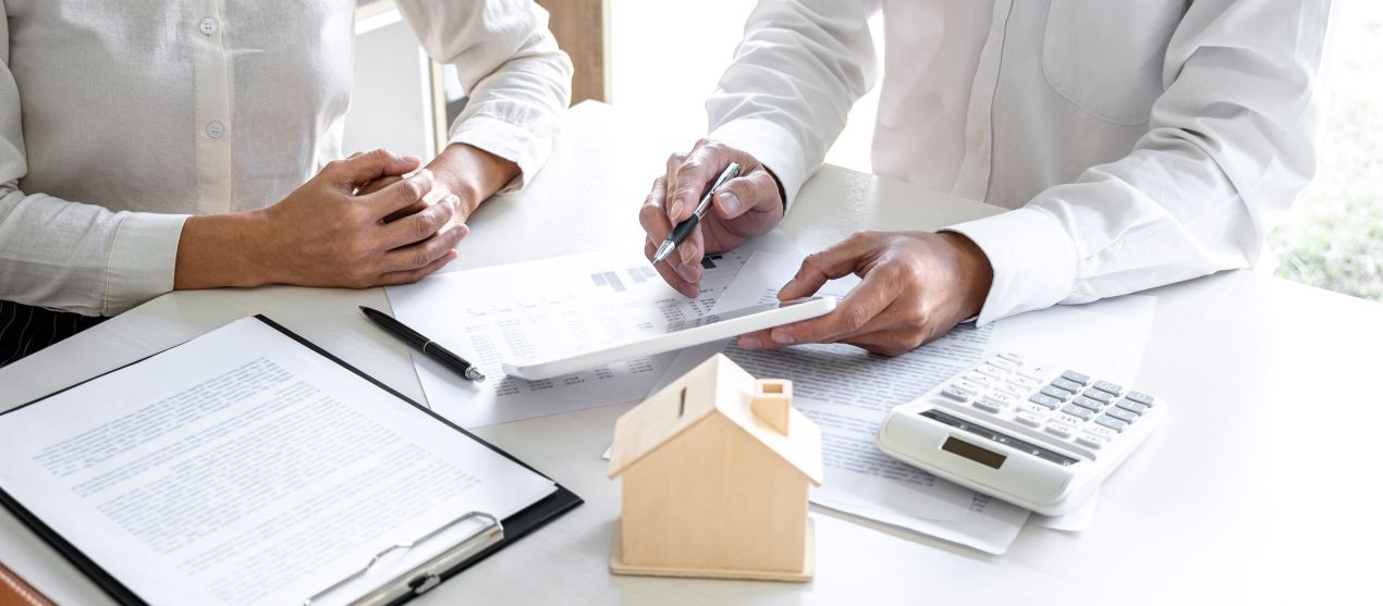 Zwei Personen besprechen Unterlagen mit Diagrammen und Miniaturhaus - Immobilienbewertung Reutlingen und neutrale Fachberatung
