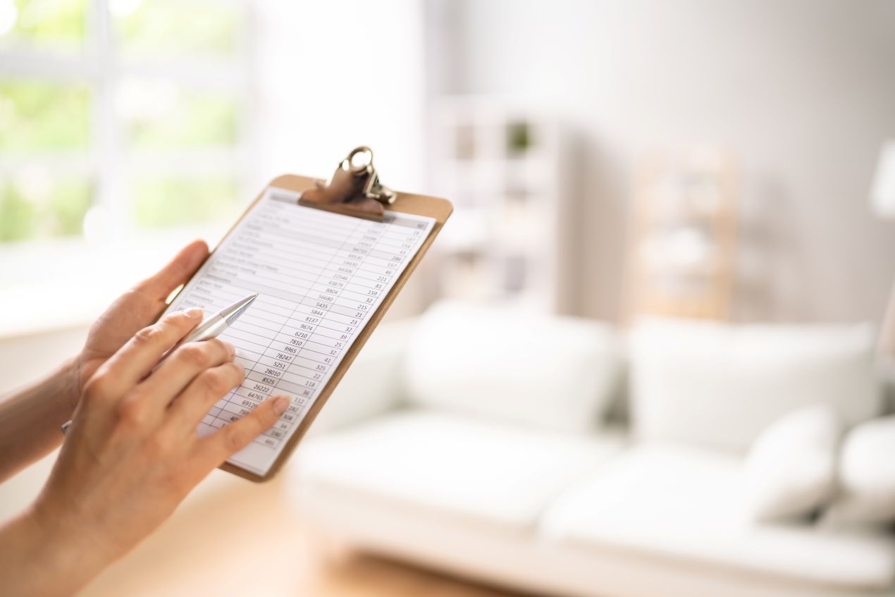 Person hält Klemmbrett mit Bewertungsbogen in modernem Wohnzimmer – Symbolbild für Immobilienbewertung Reutlingen und systematische Objektanalyse