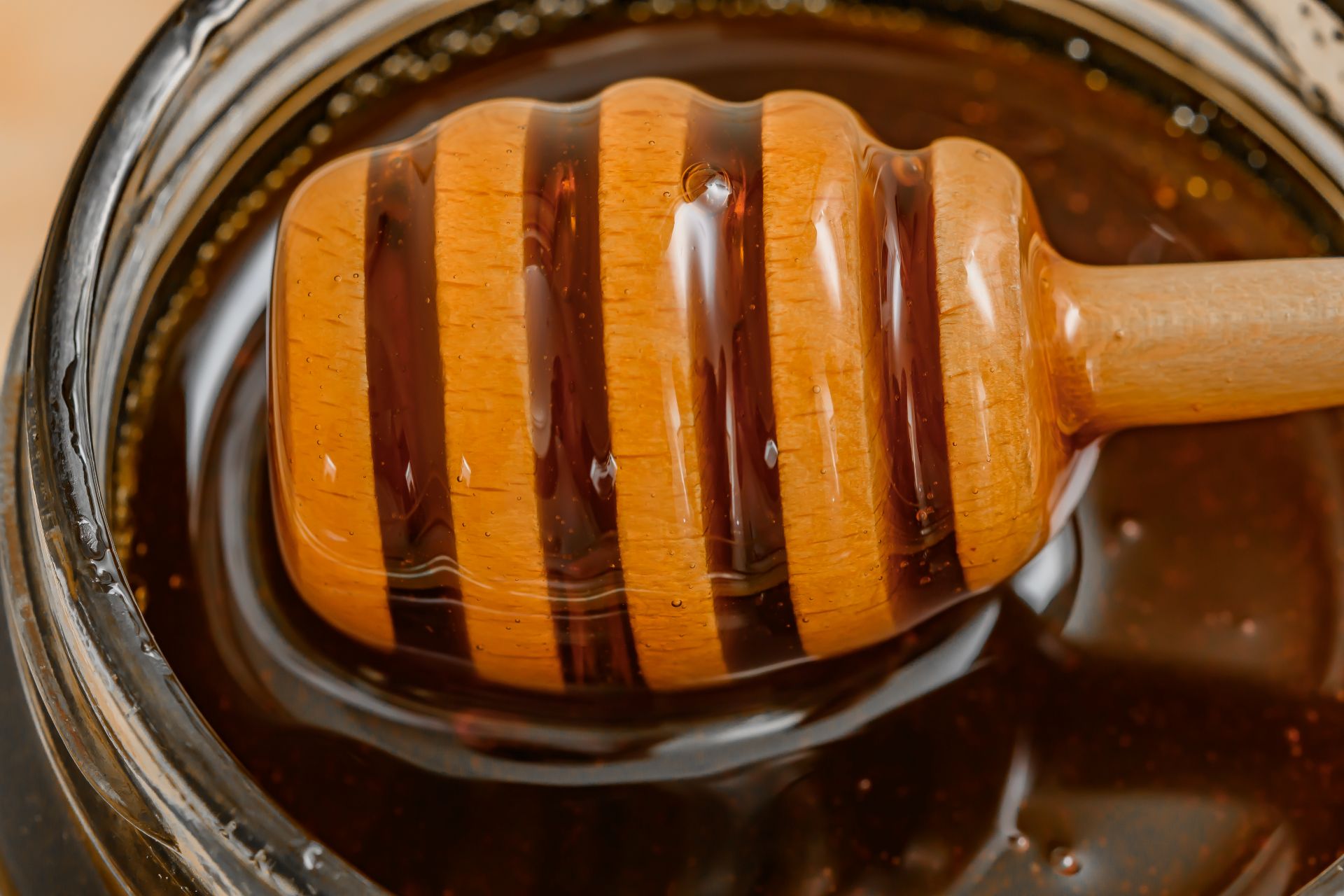 Holzlöffel mit dickflüssigem dunklem Honig in einem Glas aus der Nähe fotografiert