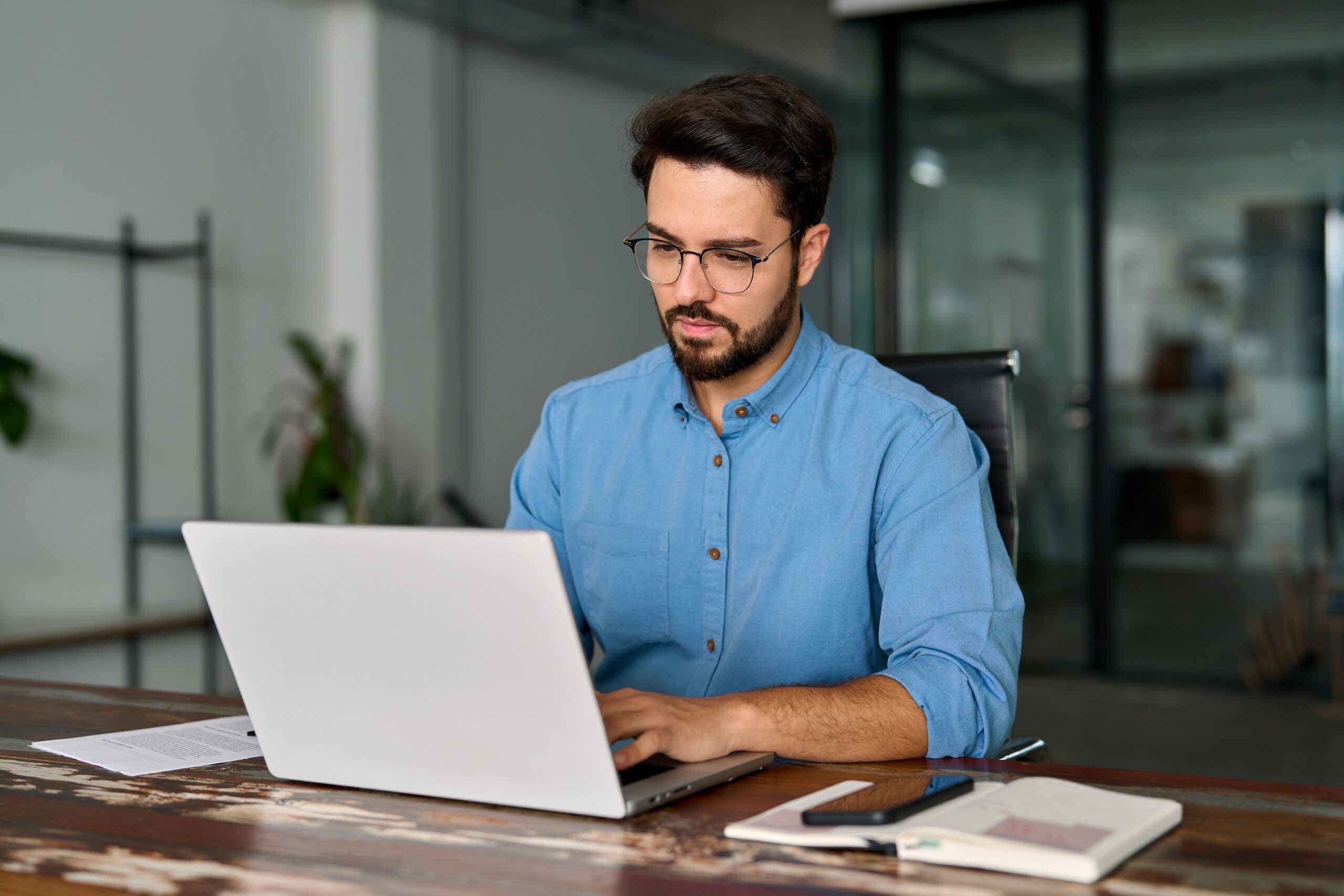 Mann im Büro analysiert Daten am Laptop – Qualitätsmanagement mit digitalen Methoden und KI Lösungen